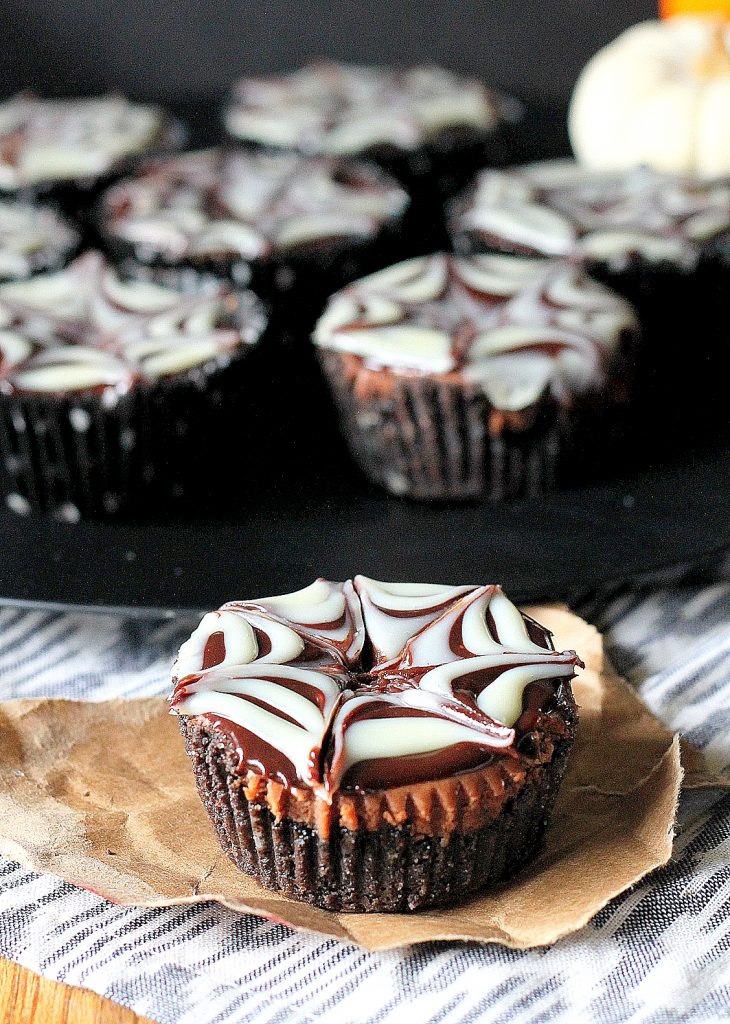 These Death by Chocolate Mini Cheesecakes have an Oreo cookie crust, a creamy chocolate cheesecake studded with chocolate chips, all topped with a chocolate ganache spiderweb.