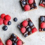 These Chocolate Berry Bars have an almond flour crust topped with vegan chocolate ganache and fresh raspberries and blueberries. These dessert bars are beautiful, delicious, and better for you - they're gluten-free, vegan, refined sugar-free, and Paleo.