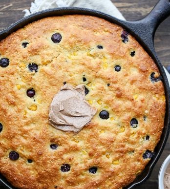 This Blueberry Cornbread is a sweeter take on traditional cornbread with fresh blueberries and sweet corn kernels. It's baked in a skillet and served with whipped cinnamon honey butter.
