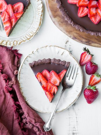 This Strawberry Chocolate Tart is filled with vegan chocolate ganache and topped with fresh strawberries, all in a chocolate crust. Slice into this easy and delicious gluten-free, Paleo, and vegan dessert.