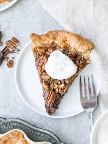 This Paleo Chocolate Pecan Pie has a flaky grain-free pie crust and a layer of chocolate ganache! This gluten-free and refined sugar-free pie is gooey, crunchy, and the perfect addition to your holiday dessert line-up.