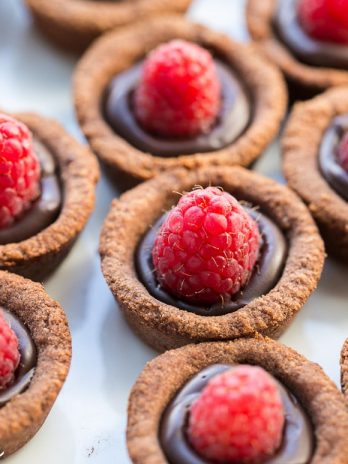 These Chocolate Raspberry Tartlets are super chocolatey bites - they have a chocolate shortbread crust filled with chocolate ganache and topped with a fresh raspberry. Satisfy your chocolate craving with one of these gluten-free, Paleo + vegan tartlets.