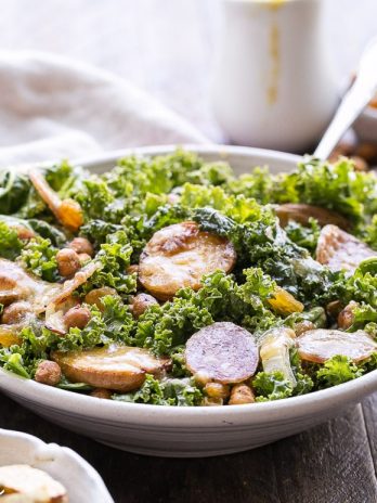 This Kale & Salami Salad with Roasted Garlic Vinaigrette is loaded with roasted fingerling potatoes, crispy toasted chickpeas, golden raisins, and caramelized onions! This filling salad makes the perfect lunch or dinner. It's gluten free and dairy free, with a Paleo option.