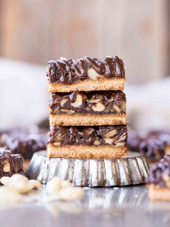 These Salted Chocolate Mixed Nut Bars are a scrumptious dessert bar that has a gooey, nutty center on top of a shortbread crust, topped with dark chocolate and flaky sea salt. These gluten free, paleo, and vegan bars are an irresistible way to satisfy your sweet tooth.