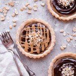 These Chocolate Peanut Butter Caramel Tarts have a crunchy shortbread crust that's filled with a creamy peanut butter date caramel and topped with creamy chocolate ganache! This decadent tart recipe is gluten-free, grain-free and vegan.