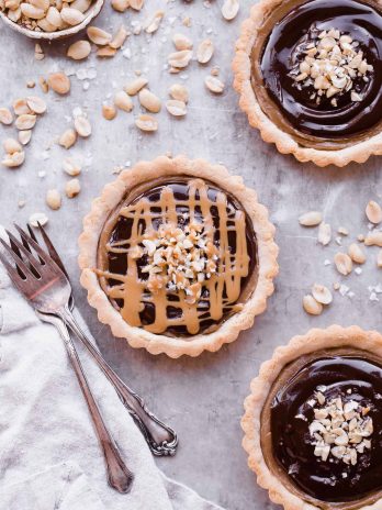 These Chocolate Peanut Butter Caramel Tarts have a crunchy shortbread crust that's filled with a creamy peanut butter date caramel and topped with creamy chocolate ganache! This decadent tart recipe is gluten-free, grain-free and vegan.