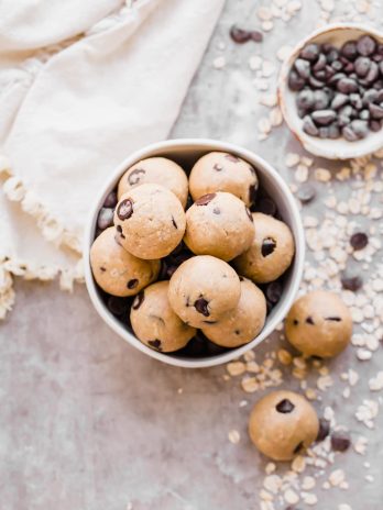 Oatmeal Chocolate Chip Cookie Dough Bites: Gluten Free & Vegan. Stacked in a bowl with oats and chocolate chips.