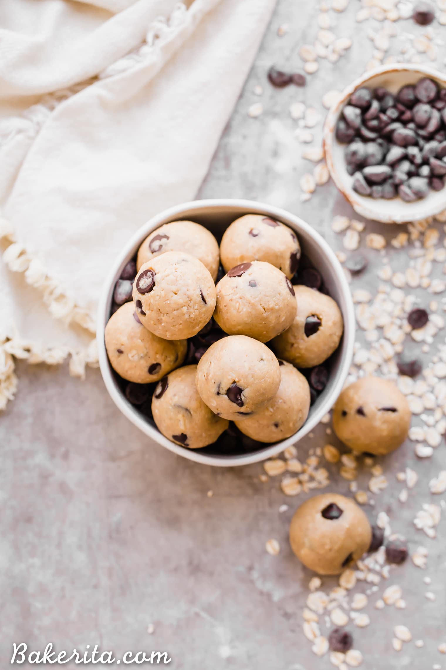 Oatmeal Chocolate Chip Cookie Dough Bites: Gluten Free & Vegan. Stacked in a bowl with oats and chocolate chips.