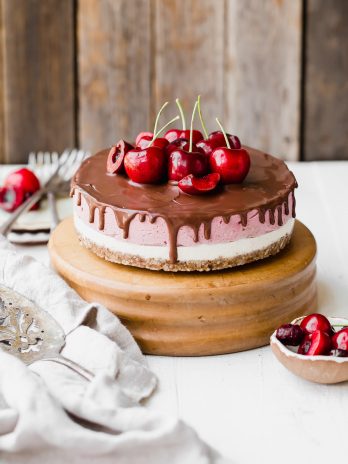 This No Bake Cherry Cheesecake has a pecan coconut crust, a layer of creamy vanilla bean cheesecake, topped by a layer of vibrant cherry cheesecake. Vegan dark chocolate ganache is spread all over the top! You'll go crazy for this gluten-free, paleo, and vegan treat.