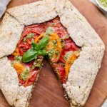 This Pesto + Heirloom Tomato Galette has an incredibly flaky, savory crust filled with homemade pesto and thick slices of heirloom tomatoes. Served warm, it's a truly delicious appetizer or meal that you'd never guess is gluten-free, paleo, and vegan.