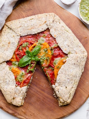 This Pesto + Heirloom Tomato Galette has an incredibly flaky, savory crust filled with homemade pesto and thick slices of heirloom tomatoes. Served warm, it's a truly delicious appetizer or meal that you'd never guess is gluten-free, paleo, and vegan.