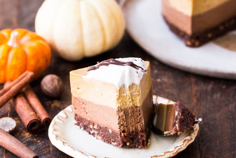 This No Bake Layered Chocolate Pumpkin Cheesecake has layers of chocolate cashew cheesecake and pumpkin spice cheesecake, on top of a chocolate date crust. This make-ahead raw dessert is perfect for the holidays.