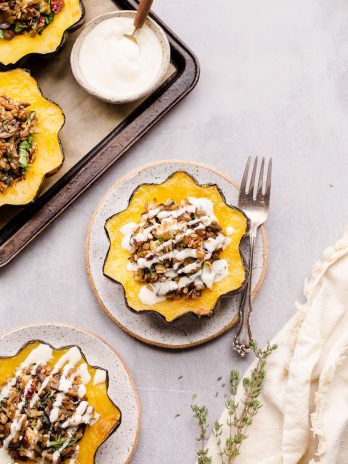 This Mushroom & Wild Rice Stuffed Acorn Squash is filled with caramelized onions, cauliflower florets, spinach, dried cranberries, and pecans. It's served with a drizzle of lemon tahini sauce. This comforting and colorful dish has a variety of texture, tons of flavor, and makes the perfect hearty dinner or side dish.