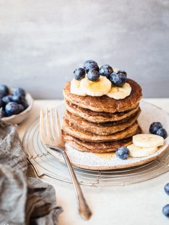 These gluten-free & vegan Banana Blueberry Pancakes are thick, fluffy, and loaded with blueberries! Made in the blender, they come together quickly and reheat well, so you can make them ahead of time for a quick breakfast.