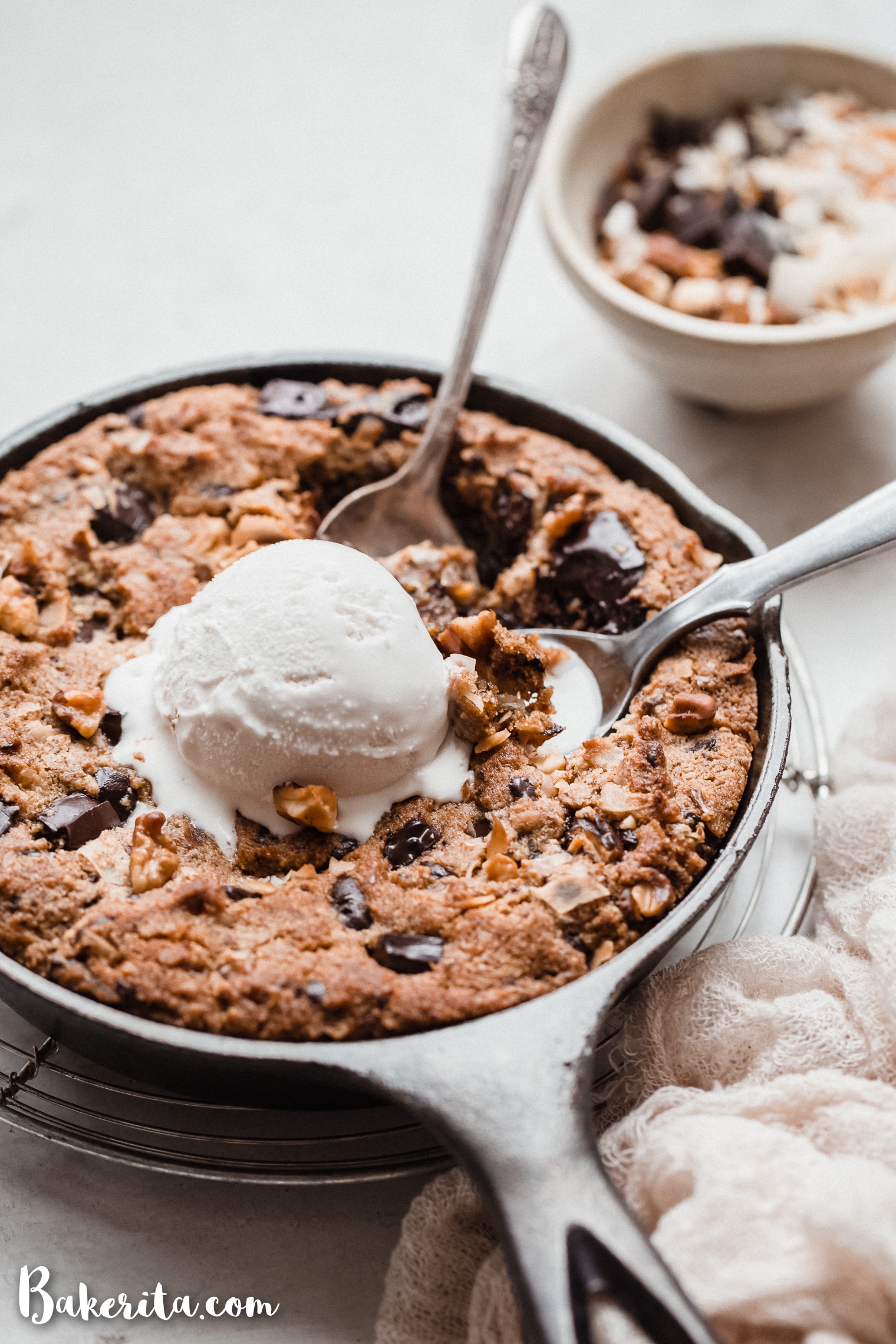 This Magic Chocolate Chip Skillet Cookie is a big, gooey and decadent gluten-free and vegan dessert. With chocolate, walnuts, and coconut, it's reminiscent of my longtime favorite, magic cookie bars. It's best topped with ice cream and so easy to make.