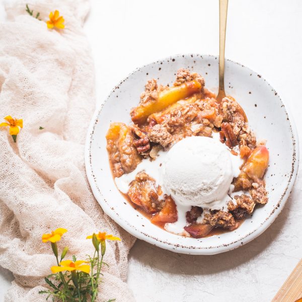 This Gluten-Free & Vegan Peach Crisp recipe is a summer staple! Scented with cinnamon and baked until bubbly, the fresh peaches are perfectly complemented by the pecan crisp topping. Top with a scoop of ice cream for the perfect dessert!