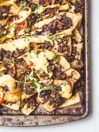 These are the BEST Vegan Nachos I've ever had! They're loaded with sauteed vegetables, vegan taco meat, pico de gallo, avocado, cilantro, and topped with a ton of vegan cheese sauce. They're the perfect cheesy snack for game day.