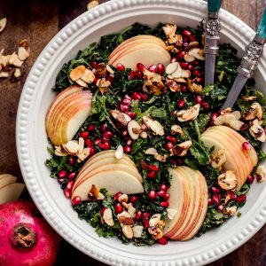 This Autumn Kale Harvest Salad brings together the best of fall's produce into a beautiful salad. With thinly sliced kale, pomegranate seeds, Honeycrisp apple slices, candied almond slices, and tossed in a lusciously sweet and tangy Apple Cider Vinaigrette. It's healthy, simple, beautiful, and the perfect accompaniment to your holiday meal or autumn dinner table.