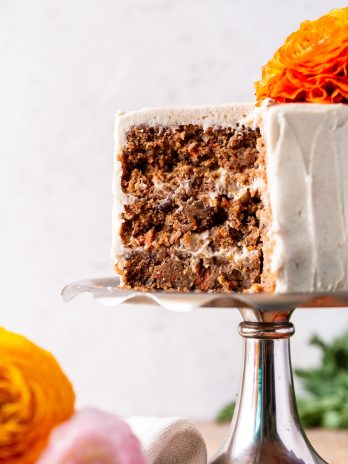 Three Layer Carrot Cake with Vegan Cream Cheese Frosting, close up of the inside of the cake, with flowers on the bottom left side.