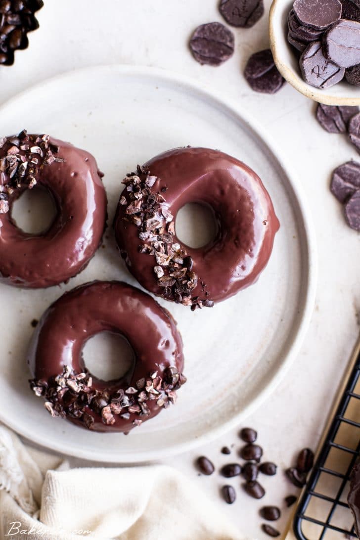 Three chocolate coffee cake donuts on a white plate.