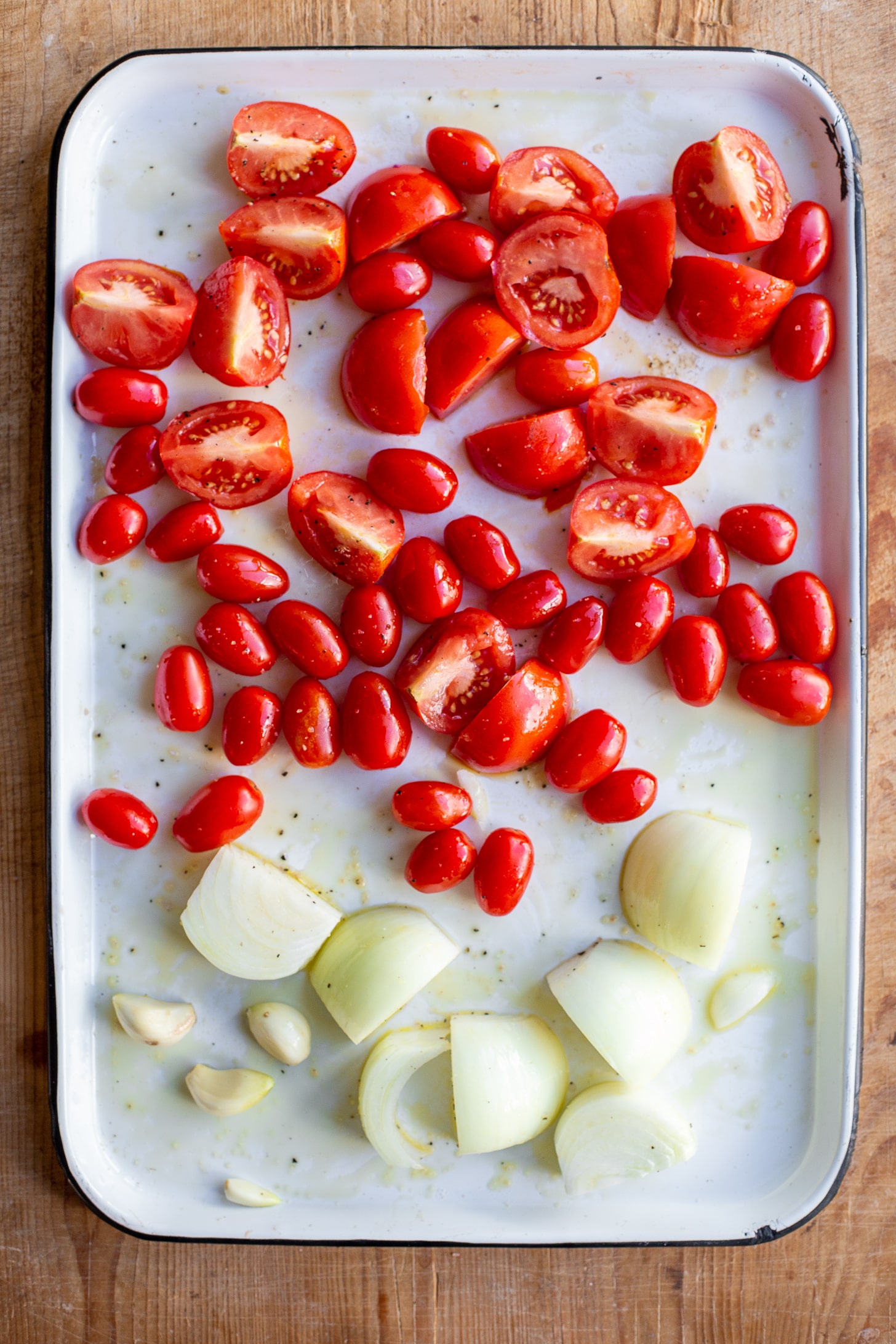 Raw tomatoes, onions and garlic on a sheet pan.