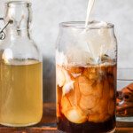 Dairy-free oat milk being poured into iced coffee sweetened with homemade horchata syrup, inspired by Starbucks horchata shaken espresso.